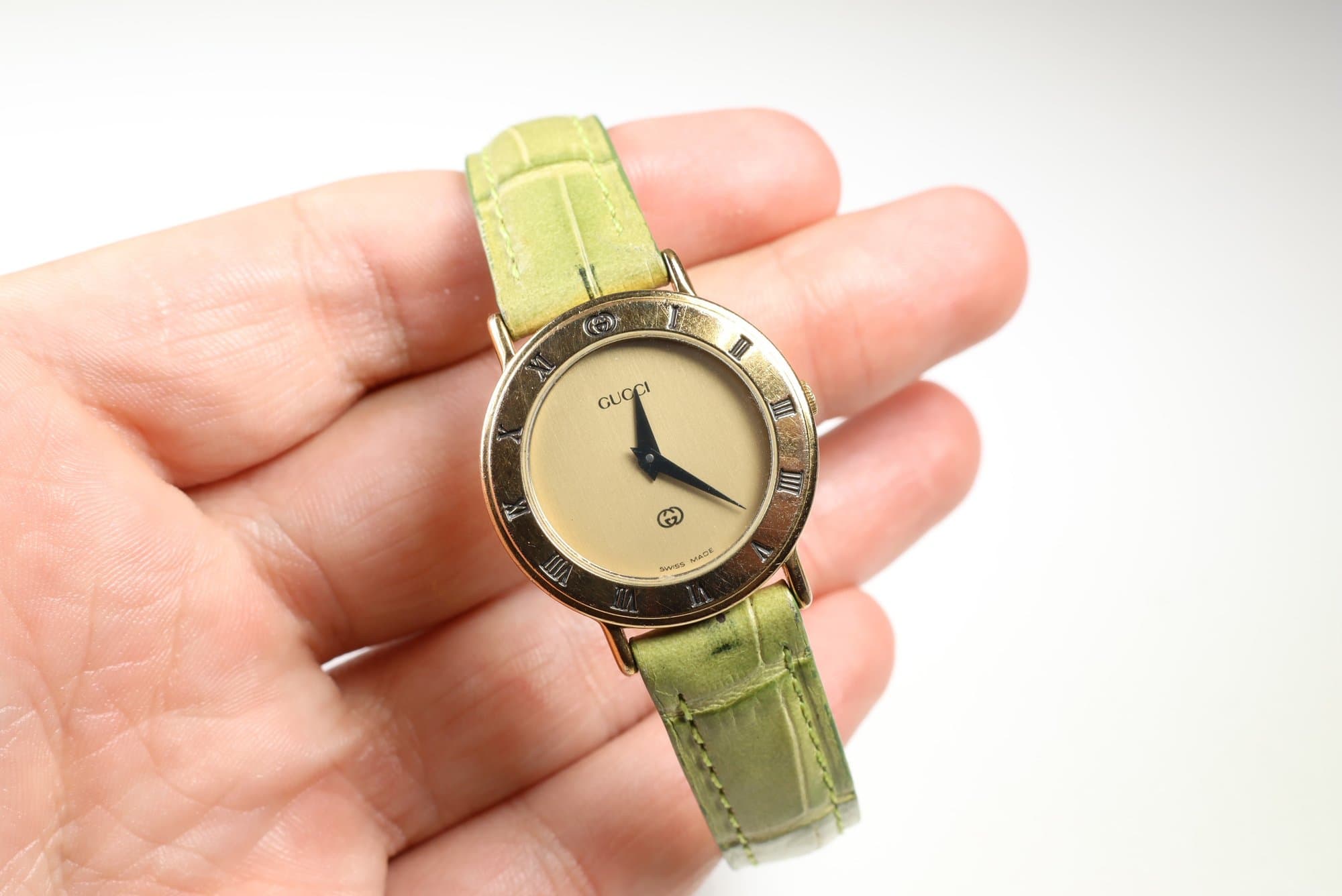 Gucci 3000L Ladies Gold-Plated Quartz Watch, Roman Numeral Bezel, Green Leather Strap watches auction on bidia.ai